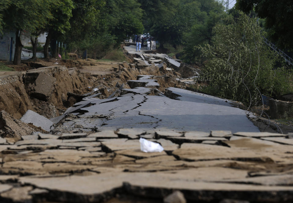 Local residents examine a damaged portion of a road caused by a powerful earthquake, in Jatlan near Mirpur, in northeast Pakistan, Wednesday, Sept. 25, 2019. Thousands of people whose homes were damaged because of a strong earthquake are desperately waiting for the arrival of government help, 22 hours after the 5.8 magnitude tremor struck Pakistan-held Kashmir and elsewhere, killing 25 people and injuring 700. (AP Photo/Anjum Naveed)