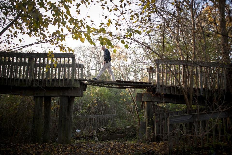 In this Monday, Dec. 9, 2013 photo, Homeless Liaison Officer Tom Gentner walks on a makeshift drawbridge outside an abandoned building while checking on people living in the structure in Savannah, Ga. The owner asked Gentner to evacuate the building so it can be donated to the fire department for training exercises. (AP Photo/Stephen B. Morton)