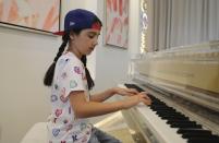 Michelle Rasul plays piano in the lobby of her apartment building in Dubai, United Arab Emirates, Sunday, May 9, 2021. Rasul, a 9-year-old girl from Azerbaijan who lives in Dubai, is scratching her way to the top as a DJ after competing in the DMC World DJ Championship. (AP Photo/Kamran Jebreili)