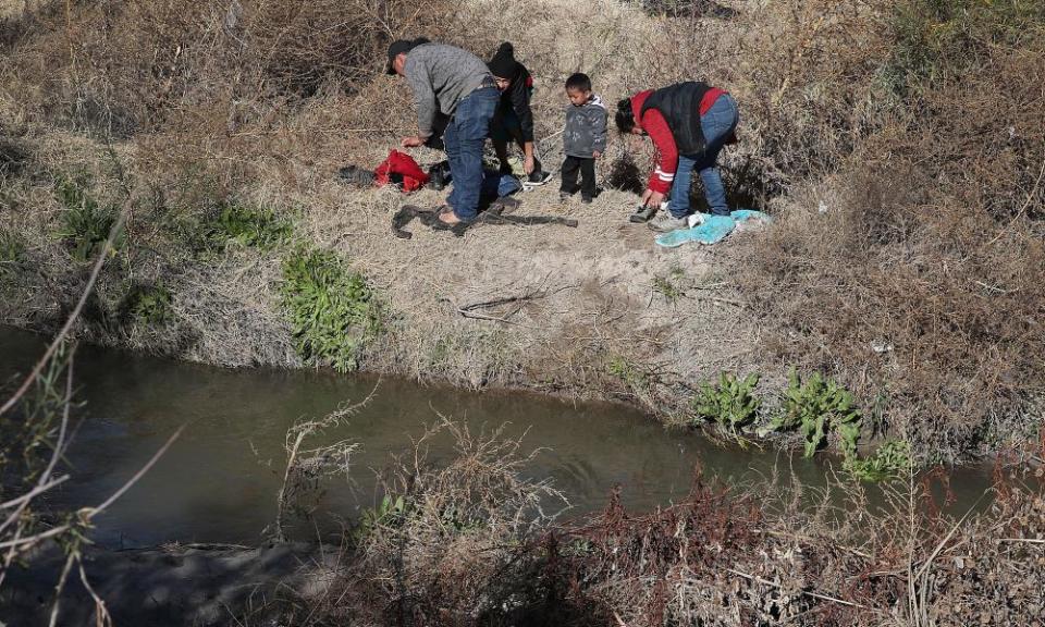 A man from Honduras and a woman and her children from Guatemala put on dry clothes after crossing part of the Rio Grande as they prepare to turn themselves over to US border patrol, on 13 January.