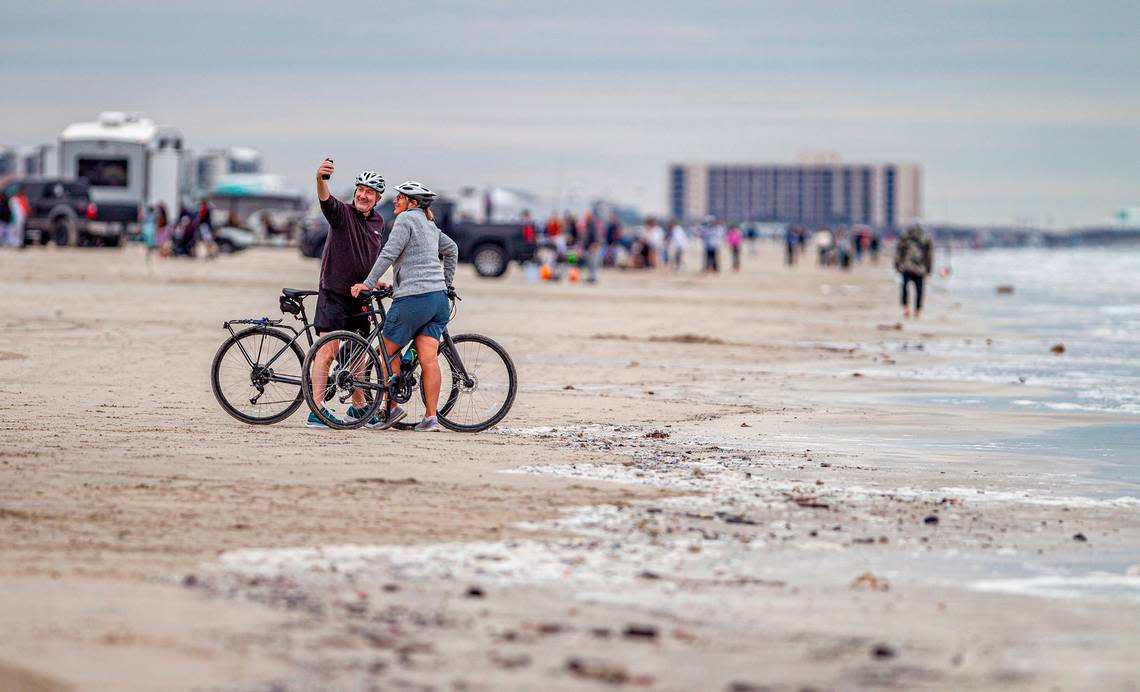 A couple on bicycles take a snapshot of themselves on the sand. Many Texans spent their Thanksgiving Day on the beach in Port Aransas Thursday, Nov. 23, 2023.