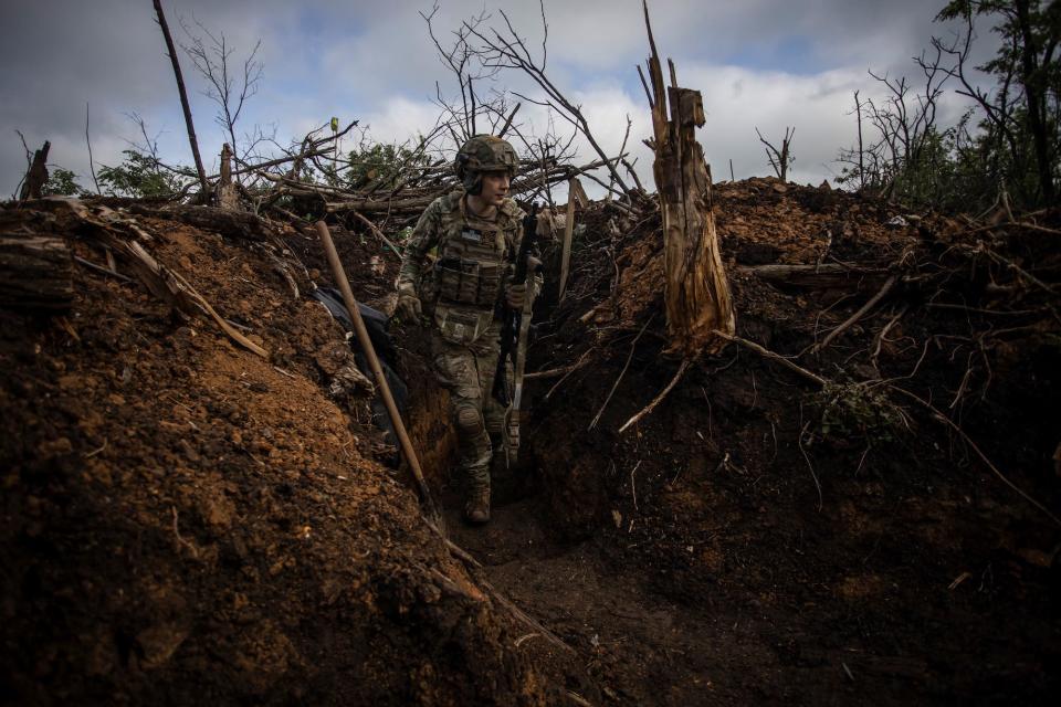 A Ukrainian serviceman walks in a trench at a position