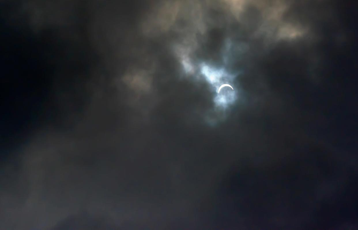 Dark clouds nearly cover a partial solar eclipse.