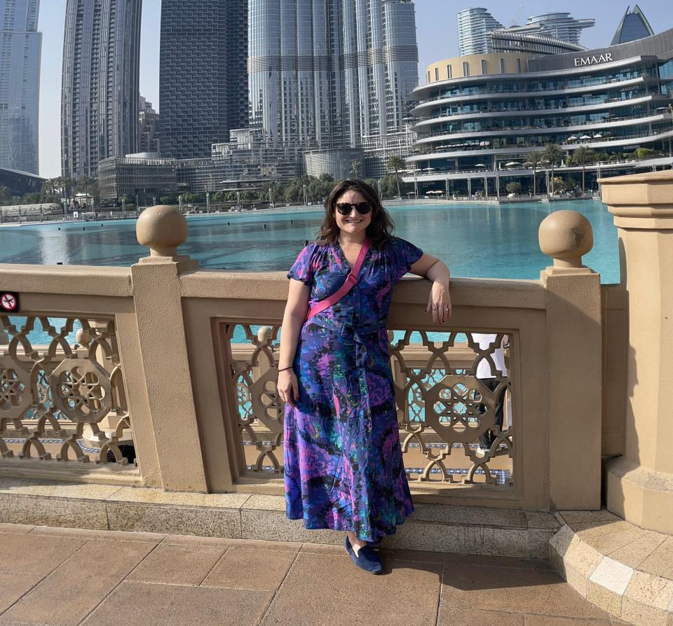 Catherine Boudreau wears a long, colorful maxi dress in front of the Burj Khalifa in Dubai.