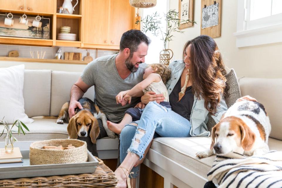 The family sitting on the couch with two dogs at The Tiny Canal Cottage by Whitney Leigh Morris