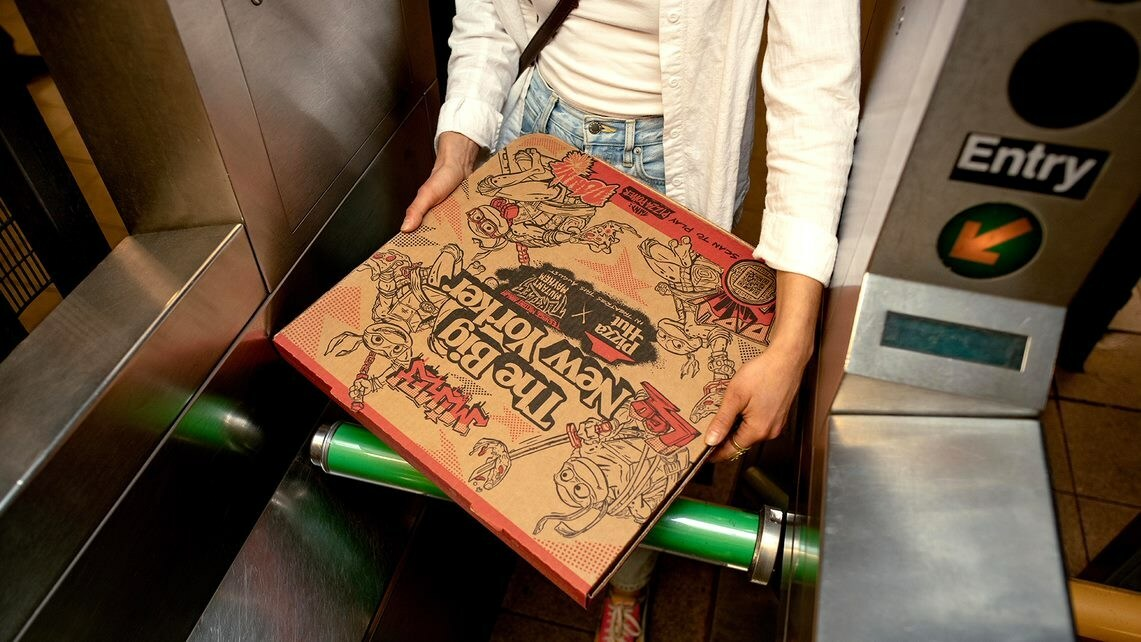 A woman carrying a Pizza Hut box in the NYC subway