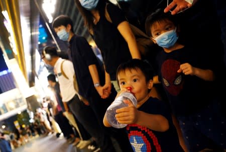 A child drinks from a bottle as protesters hold hands to form a human chain during a rally to call for political reforms in Hong Kong's Central district