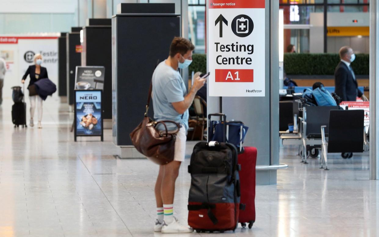 A passenger stands next to a Covid testing centre sign at Heathrow Airport - Peter Nicholls/Reuters