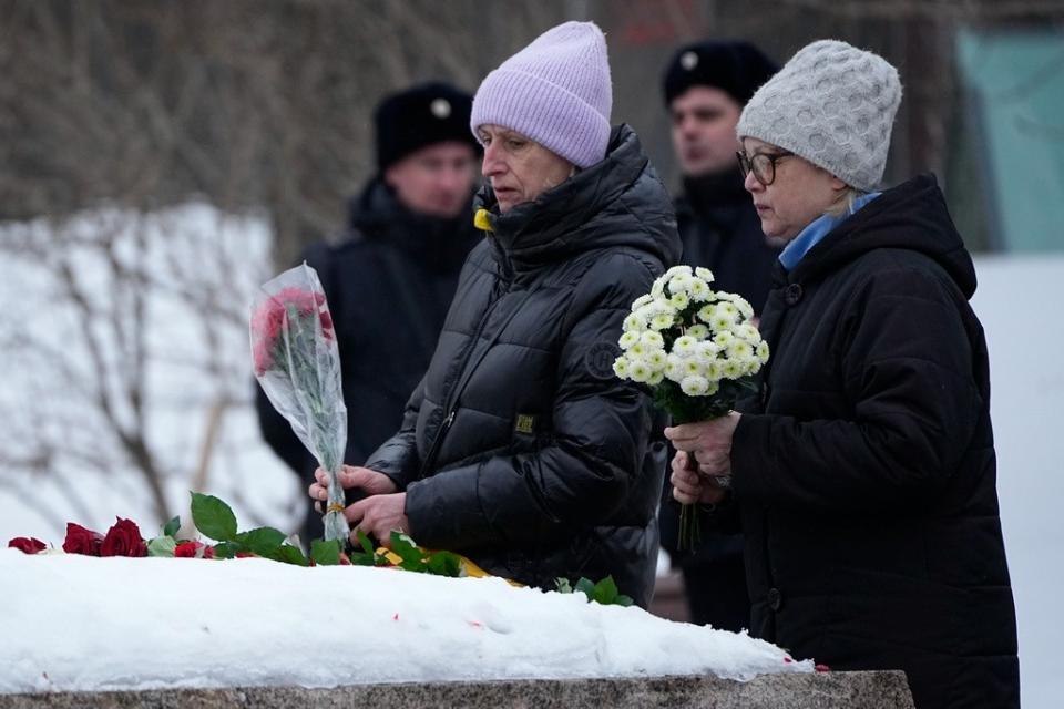俄國民眾2月24日在莫斯科的「索羅維茨基石碑」獻花，藉以悼念16日猝逝獄中的納瓦尼。民眾後方有警察戒備。美聯社