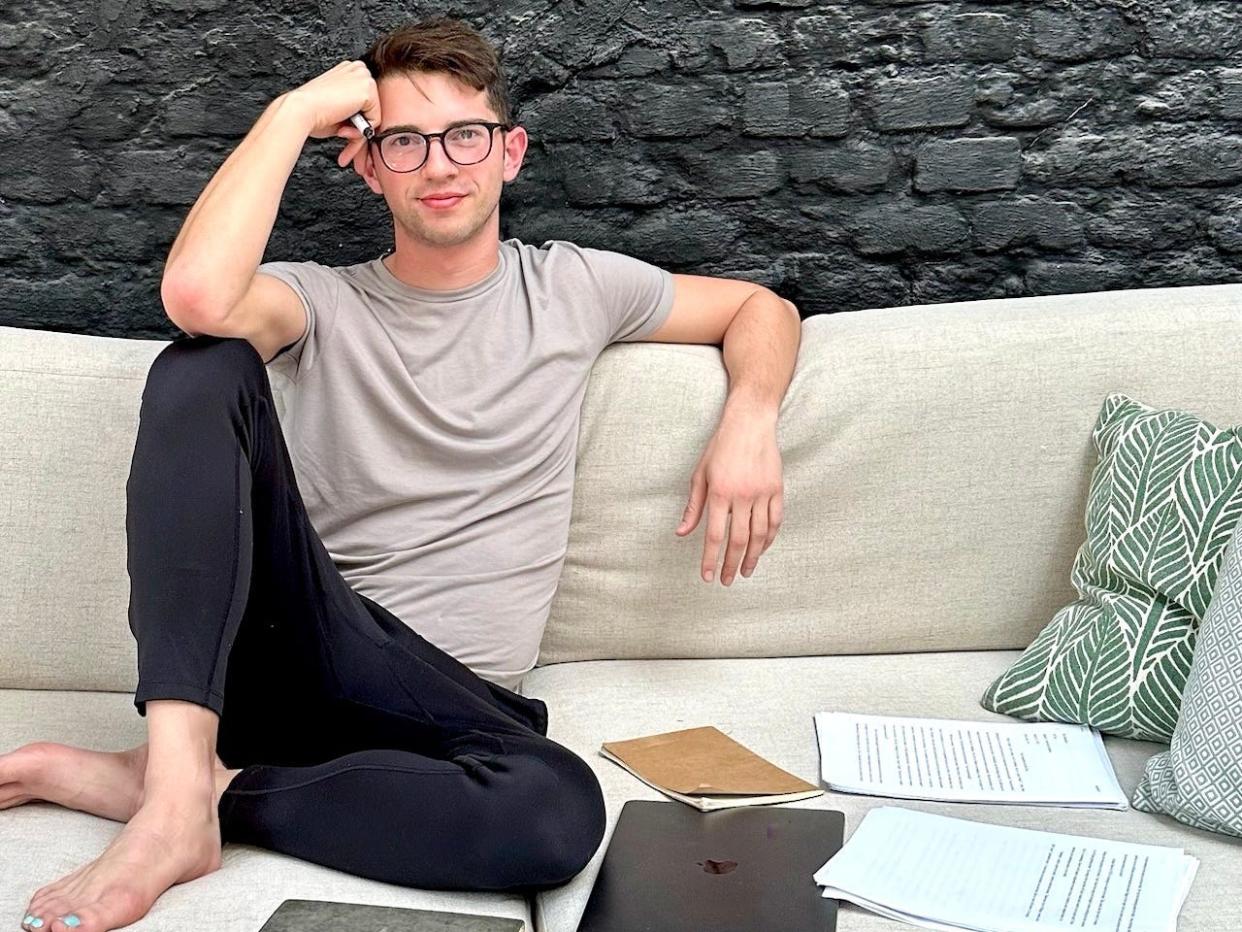 Austin Roy siting on a couch with papers and laptop next to him