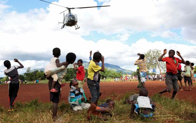 Children in Mulanje look on as a military helicopter carry doctors and medical supplies to Muloza on the border with Mozambique which are cut off after the tropical Cyclone Freddy outside Blantyre, Malawi - ESA ALEXANDER/REUTERS