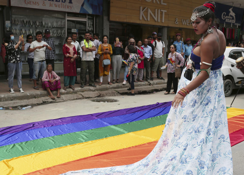 In this Aug. 16, 2019, photo, a participant stands beside a rainbow flag before a gay pride parade in Kathmandu, Nepal. Nepal seized the lead in equal rights for sexual minorities in South Asia four years ago with a new constitution that forbids all discrimination based on sexual orientation. But activists say progress in equal rights has stalled since the constitution was adopted. (AP Photo/Niranjan Shrestha)