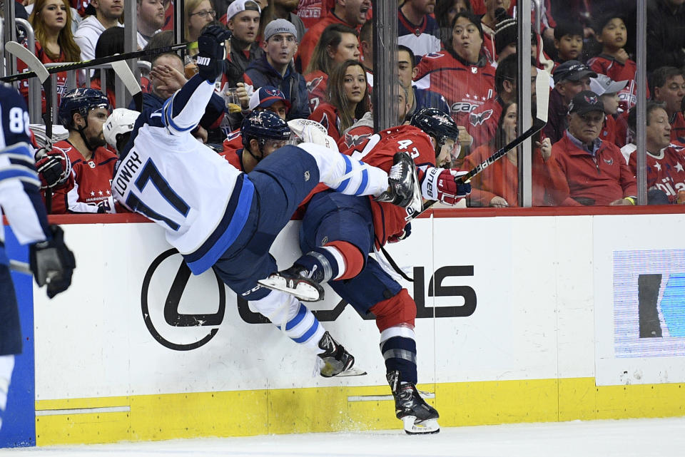 Washington Capitals right wing Tom Wilson (43) and Winnipeg Jets center Adam Lowry (17) collide along the boards during the first period of an NHL hockey game, Sunday, March 10, 2019, in Washington. (AP Photo/Nick Wass)