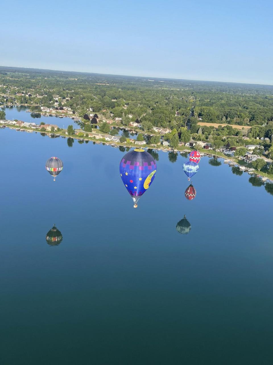 A group of hot air balloons fly over a lake at the Women's National Competition in Jackson, Missouri, in July.