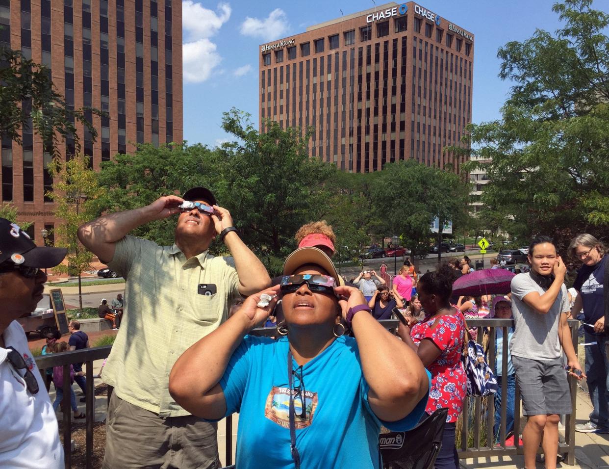 David Walker (left) and Alicia Hammett, (center) both from Akron get their first look at the solar eclipse at the Akron-Summit County Public Library in downtown Akron, Monday, Aug. 21, 2017. (File/Akron Beacon Journal)