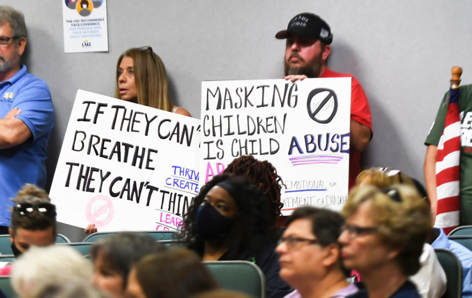 People demonstrate with placards at a school board meeting.