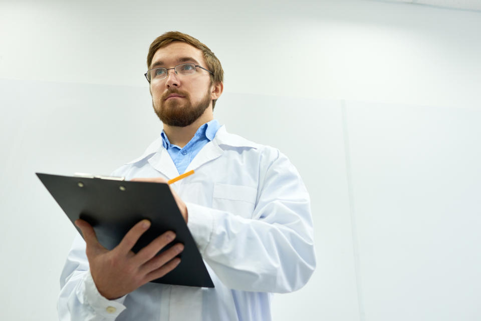 Guy in a lab coat taking notes with a clipboard.