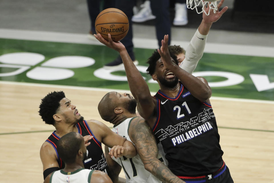 Philadelphia 76ers' Joel Embiid (21) is fouled as he shoots against multiple Milwaukee Bucks' defenders during the second half of an NBA basketball game Thursday, April 22, 2021, in Milwaukee. (AP Photo/Aaron Gash)