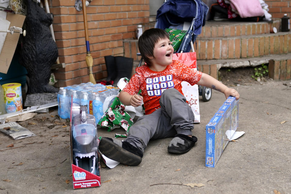 Conner Bourque reacts as he opens Christmas presents brought by church volunteers, where he lives with his family in a camper outside their heavily damaged home, in the aftermath of Hurricane Laura and Hurricane Delta, in Lake Charles, La., Friday, Dec. 4, 2020. (AP Photo/Gerald Herbert)