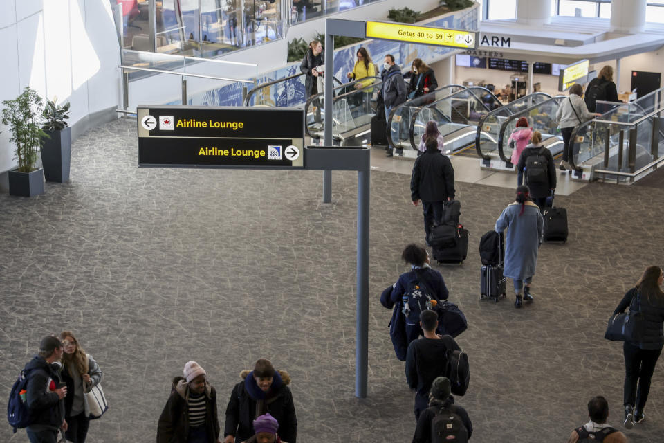 Travelers walk through LaGuardia Airport's Terminal B, Tuesday, Nov. 22, 2022, in New York. Travel experts say the ability of many people to work remotely is letting them take off early for Thanksgiving or return home later. Crowds are expected to rival those of 2019, the last Thanksgiving before the pandemic. (AP Photo/Julia Nikhinson)