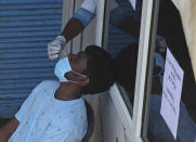 A health worker takes a nasal swab sample of a man to test for COVID-19 at a hospital in Hyderabad, India, Friday, April 16, 2021. India reported more than 200,000 new coronavirus cases Thursday, skyrocketing past 14 million overall as an intensifying outbreak puts a grim weight on its fragile health care system. (AP Photo/Mahesh Kumar A.)