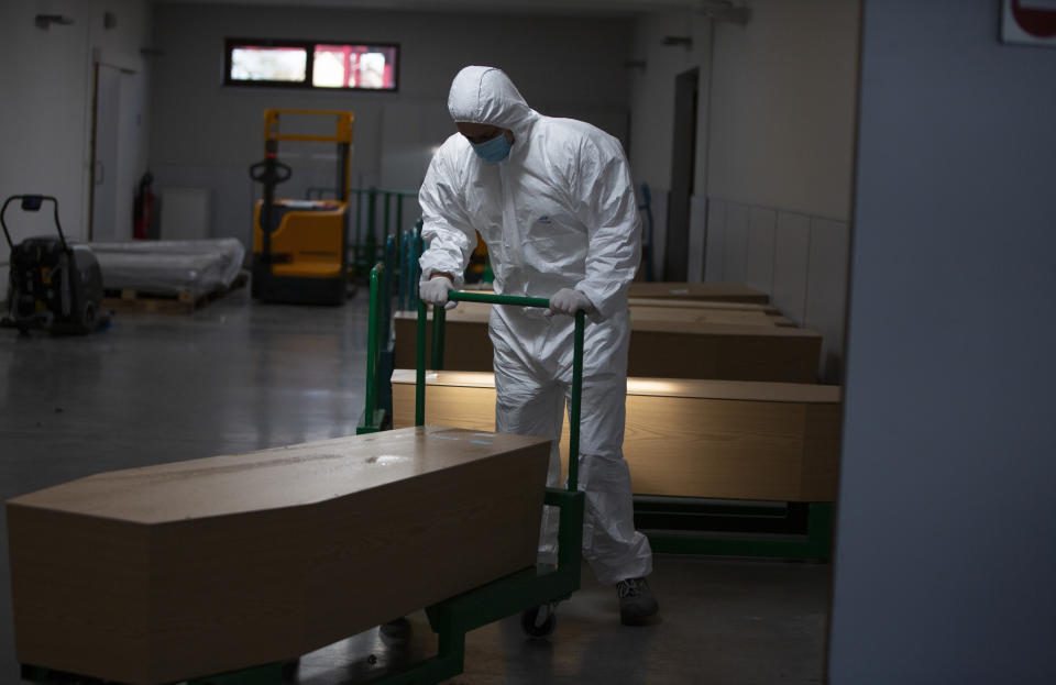 FILE - In this Friday, April 3, 2020 file photo, a worker in protective gear moves a casket of a Covid-19 deceased at the Pontes crematorium and funeral center in Wilrijk, Belgium. This week news struck that the European Center for Disease Control has put Belgium at the largest number of COVID-19 cases per 100,000 citizens, surpassing the Czech Republic, it is revealed Tuesday Oct. 27, 2020. (AP Photo/Virginia Mayo, File)