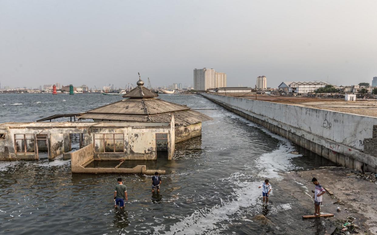 A derelict mosque by a protective sea wall in northern Jakarta has become a symbol of the sinking city - Graham Crouch