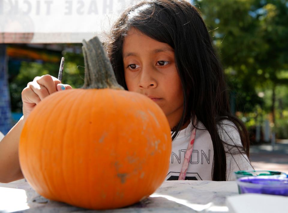 Evoleth Ayala, 9, paints a pumpkin at Pumpkinville at the Myriad Botanical Gardens in Oklahoma City, Tuesday, Oct., 10, 2023.