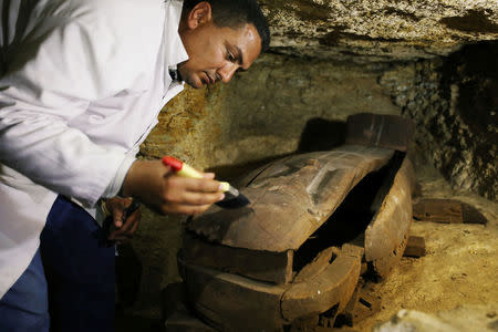 Egyptian antiquities worker brushes a coffin inside the recently discovered burial site in Minya, Egypt February 24, 2018. REUTERS/Mohamed Abd El Ghany