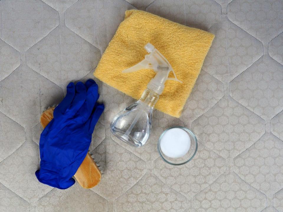 overhead view of mattress with cup of baking soda and other cleaning supplies