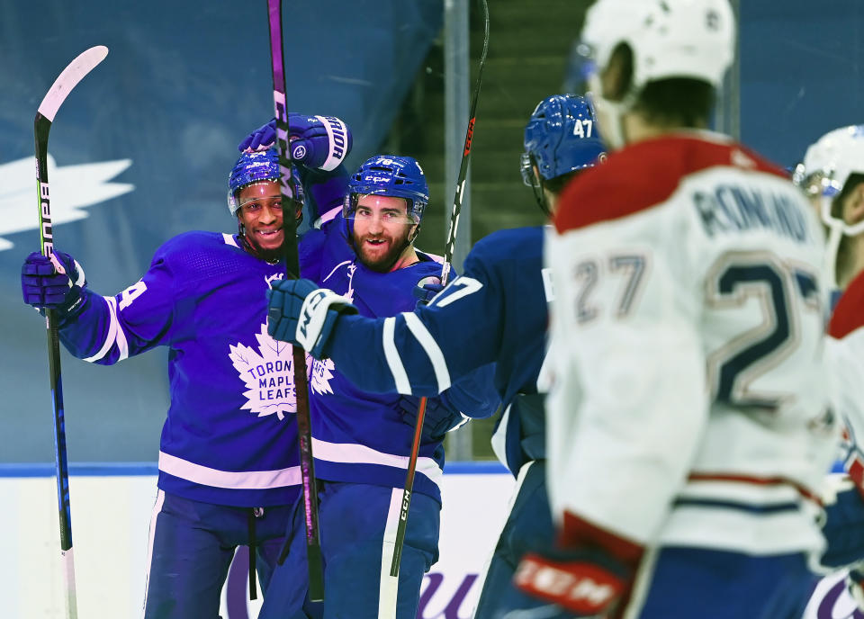 Toronto Maple Leafs defenseman TJ Brodie (78) celebrates his goal with teammate Wayne Simmonds (24) as Montreal Canadiens defenseman Alexander Romanov (27) looks on during the third period of an NHL hockey game Wednesday, April 7, 2021, in Toronto. (Nathan Denette/The Canadian Press via AP)