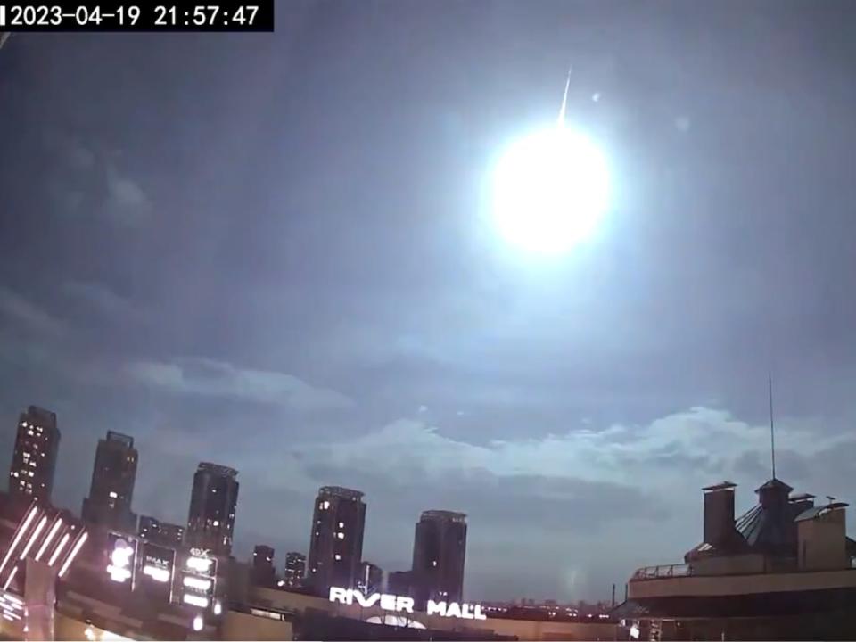 A screengrab shows a flash of light in front of an illuminated tail over the cityscape of Kyiv. The timestamp reads 2023-04-19 21:7:47