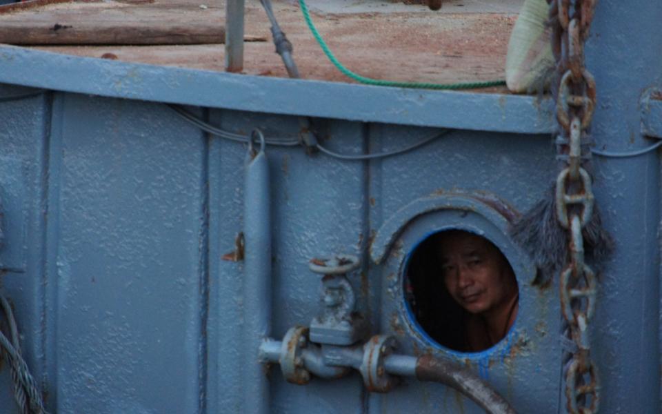 A Chinese fisherman peers from a fishing boat at the mouth of the Yalu River, yards from North Korea  - Neil Connor/The Telegraph