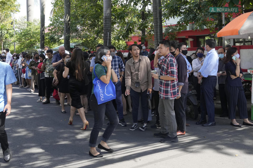 People wait outside an office building after being evacuated following an earthquake, Monday, Nov. 21, 2022, at the main business district in Jakarta, Indonesia. An earthquake shook Indonesia's main island of Java on Monday damaging dozens of buildings and sending residents into the capital's streets for safety. (AP Photo/Tatan Syuflana)