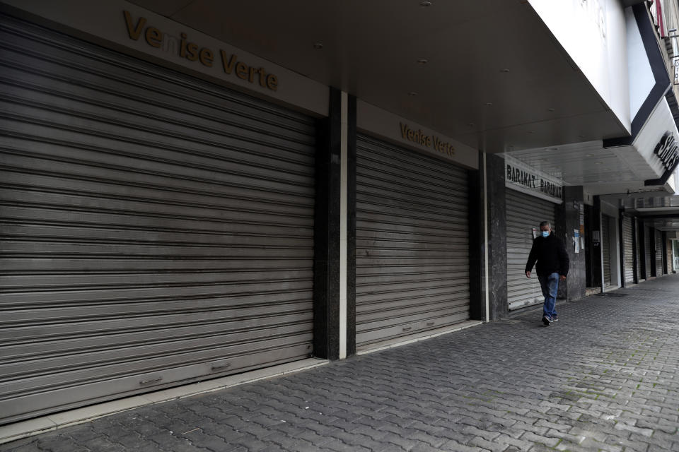 A man walks past closed shops as the country starts a new lockdown, in Beirut, Lebanon, Thursday, Jan. 14, 2021. Lebanese authorities began enforcing an 11-day nationwide shutdown and round the clock curfew Thursday, hoping to limit the spread of coronavirus infections spinning out of control after the holiday period. (AP Photo/Bilal Hussein)