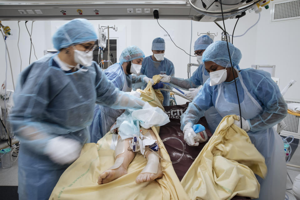 Nurse Nadia Boudra, left, Doctor Alexy Tran Dinh, center, and nurse Yvana Faro, right, care for a patient inside an operating room transformed as a room for COVID-19 unconscious patients at Bichat Hospital, AP-HP, in Paris, Thursday, April 22, 2021. France still had nearly 6,000 critically ill patients in ICUs this week as the government embarked on the perilous process of gingerly easing the country out of its latest lockdown, too prematurely for those on pandemic frontlines in hospitals. President Emmanuel Macron's decision to reopen elementary schools on Monday and allow people to move about more freely again in May, even though ICU numbers have remained stubbornly higher than at any point since the pandemic's catastrophic first wave, marks another shift in multiple European capitals away from prioritizing hospitals. In France, Greece and elsewhere, the cursor is moving back toward other economic, social and educational imperatives. (AP Photo/Lewis Joly)