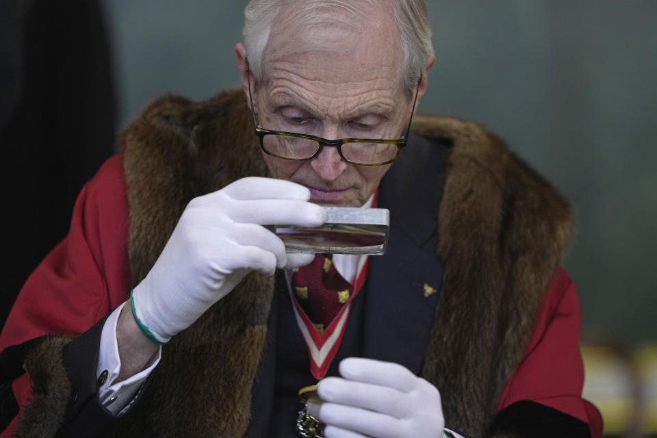 A coin is assessed during the "Trial of the Pyx,'' a ceremony that dates to the 12th Century in which coins are weighed in order to make certain they are up to standard, at the Goldsmiths' Hall in London, Tuesday, Feb. 7, 2023. A jury sat solemnly in a gilded hall in central London on Tuesday, presided over by a bewigged representative of the crown in flowing black robes, but there were no criminals in the dock. (AP Photo/Kin Cheung)