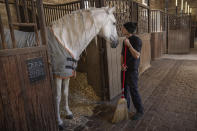 A horsewoman cleans the stables of the royal stables, in Versailles, Thursday, April 25, 2024. More than 340 years after the royal stables were built under the reign of France's Sun King, riders and horses continue to train and perform in front of the Versailles Palace. The site will soon keep on with the tradition by hosting the equestrian sports during the Paris Olympics. Commissioned by King Louis XIV, the stables have been built from 1679 to 1682 opposite to the palace's main entrance. (AP Photo/Aurelien Morissard)