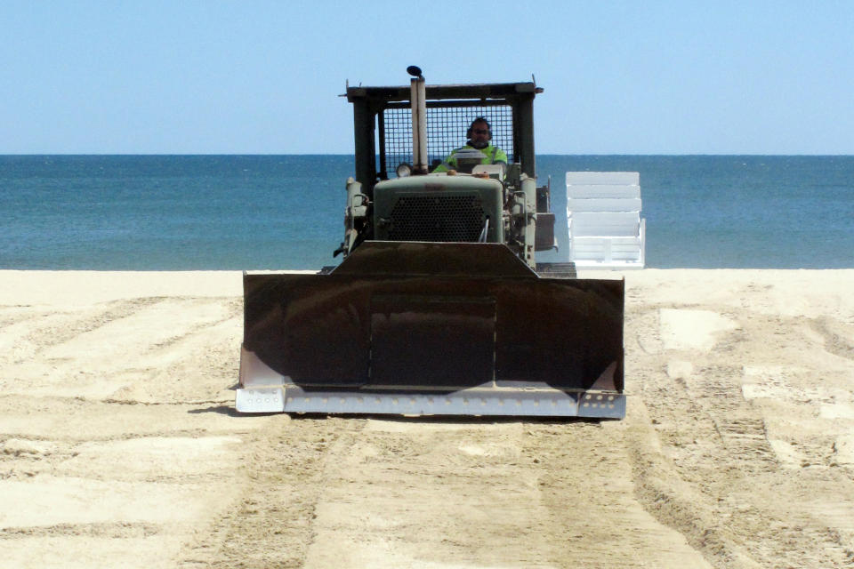 In this Tuesday, May 12, 2020 photo, workers prepare the beach in Belmar, N.J. for the summer season amid the coronavirus pandemic. Gov. Phil Murphy is expected to issue guidelines on Thursday, May 14, 2020, on when and how New Jersey's beaches can begin to reopen during the COVID-19 pandemic. (AP Photo/Wayne Parry)