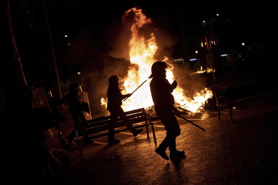 Riot police take position during clashes with Catalan pro independence protesters in Barcelona, Spain, Tuesday, Oct. 15, 2019. Spain's Supreme Court on Monday convicted 12 former Catalan politicians and activists for their roles in a secession bid in 2017, a ruling that immediately inflamed independence supporters in the wealthy northeastern region. (AP Photo/Bernat Armangue)