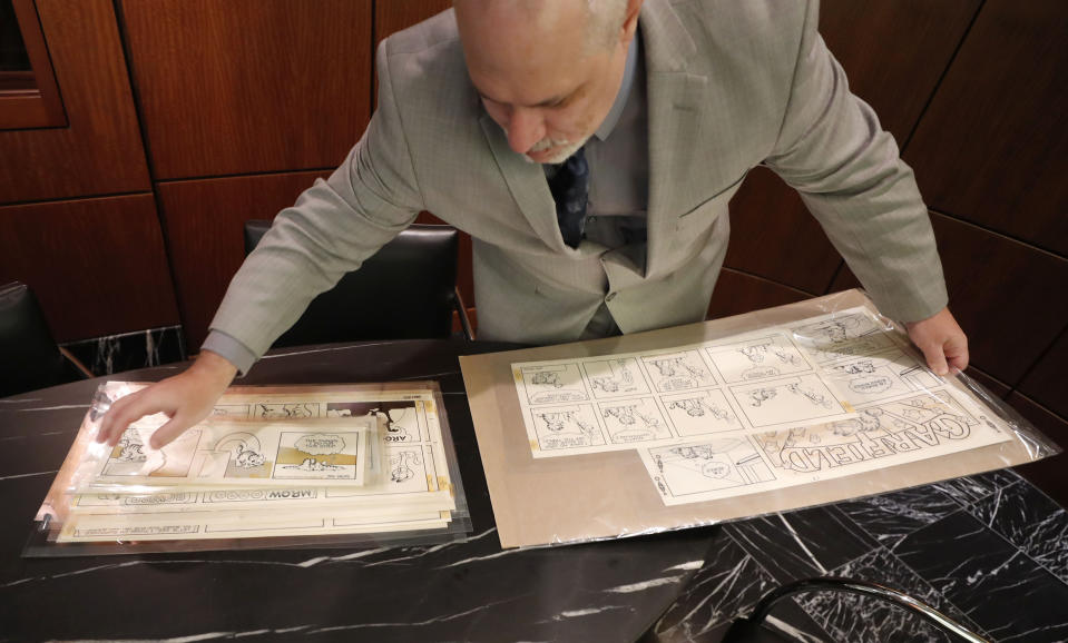 In this Monday, Nov. 18, 2019 photo, Heritage Auctions collectibles specialist Brian Wiedman displays Garfield comic artwork drawn by creator Jim Davis in Dallas. Thousands of the comics drawn by Davis are going up for auction. (AP Photo/LM Otero)