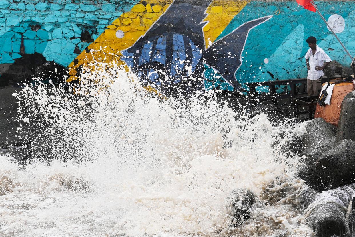 A man stands as waves hit the shore during high tide on the Arabian Sea coast in Mumbai, India (AP)