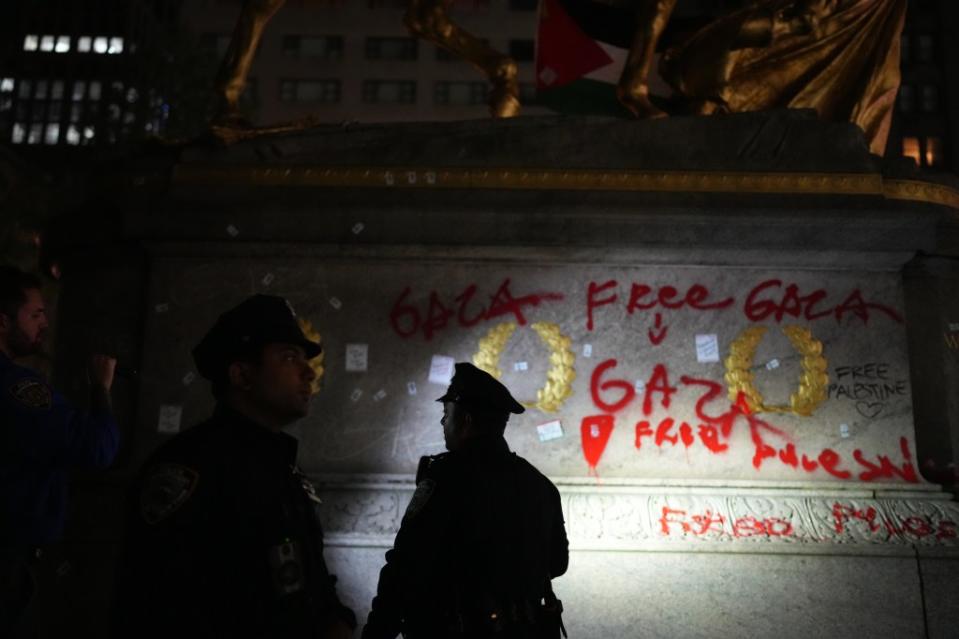 Cops stand beside the vandalized statue Monday night. James Keivom