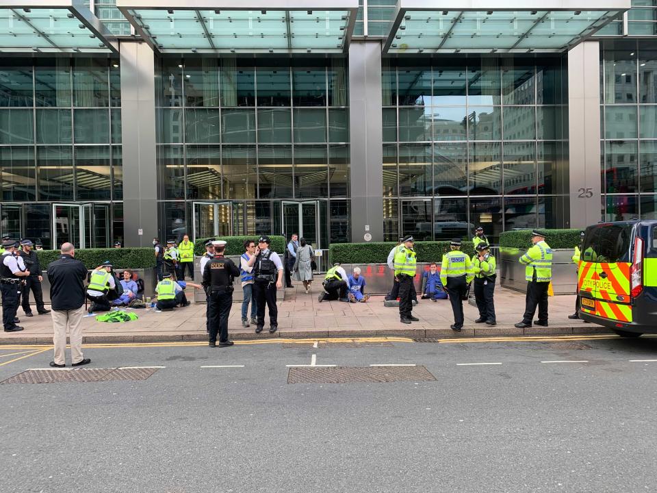 Protesters with their hands stuck to the pavement outside JP Morgan (The Independent)