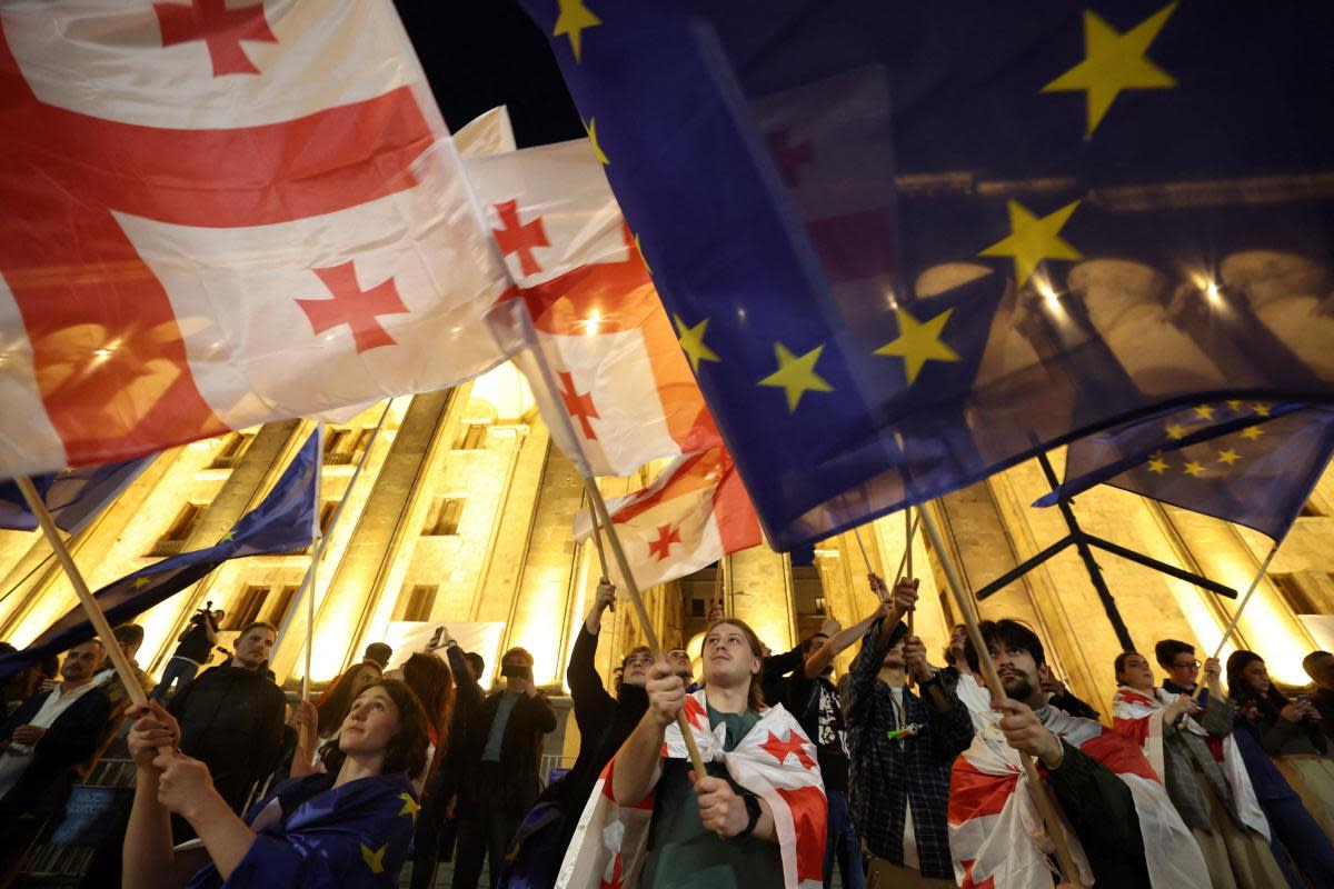 Protesters wave Georgian national and European flags during a demonstration outside the parliament building as they protest against a draft bill on "foreign influence" in Tbilisi on April 17, 2024