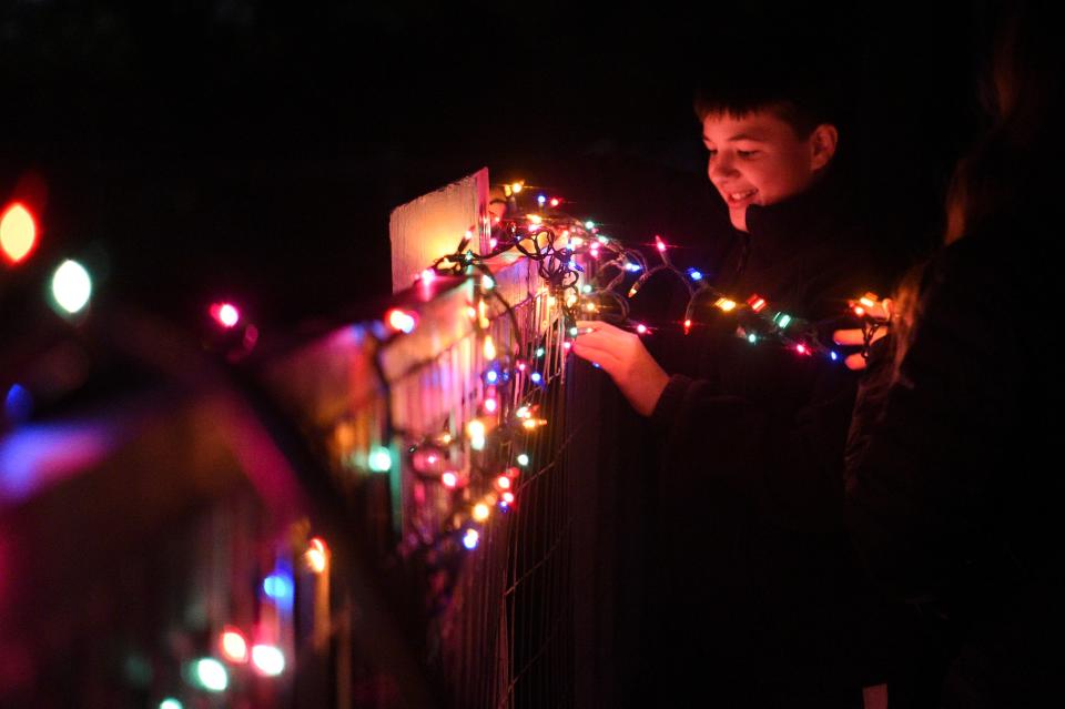 Youth from Sequoyah Hills Presbyterian decorate a home at Light Up Lonsdale, put on by Thrive, in Lonsdale, Wednesday, Nov. 29, 2023.