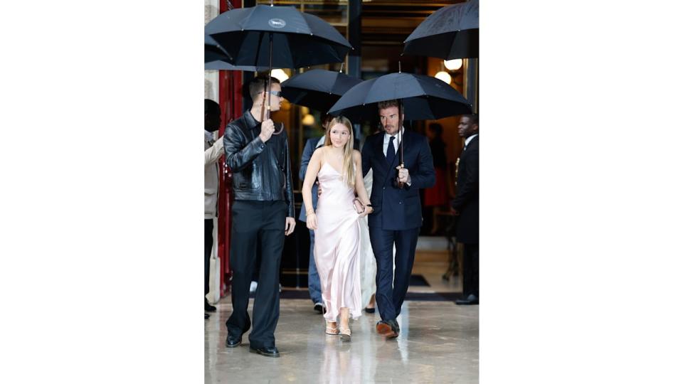 Harper wore a blush gown in the rain, walking with David and Brooklyn Beckham under umbrellas. Her delicate, flowy dress contrasted playfully with the weather, showcasing her stylish confidence.