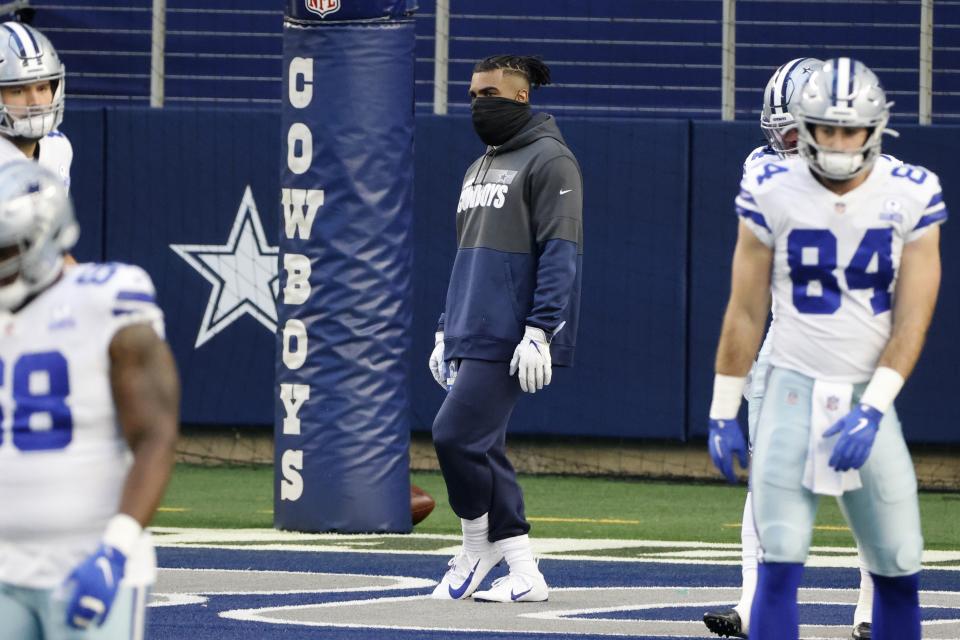 Dallas Cowboys' Ezekiel Elliott, center, watches as the team warms up for an NFL football game against the San Francisco 49ers in Arlington, Texas, Sunday, Dec. 20, 2020. Elliott is recovering from a calf injury. (AP Photo/Michael Ainsworth)