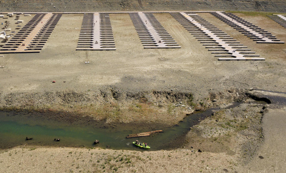 Kayakers navigate a narrow section of water near boat docks sitting on dry land at the Browns Ravine Cove area of drought-stricken Folsom Lake, currently at 37% of its normal capacity, in Folsom, Calif., Saturday, May 22, 2021. California Gov. Gavin Newsom declared a drought emergency for most of the state. (AP Photo/Josh Edelson)