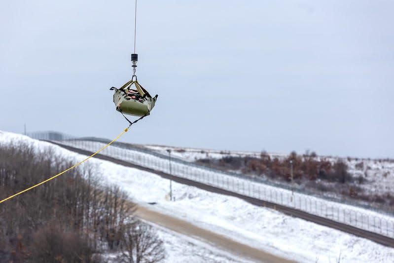 Rhode Island Army National Guard personnel work to lift a dummy patient with an airborne hoist during training in Kosovo.